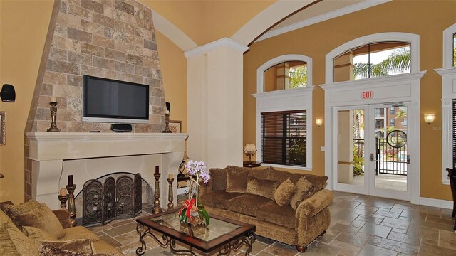 8397 38th Street Cir E Unit 306, Sarasota, FL 34243 - living area with stone tile flooring, a towering ceiling, crown molding, and decorative columns