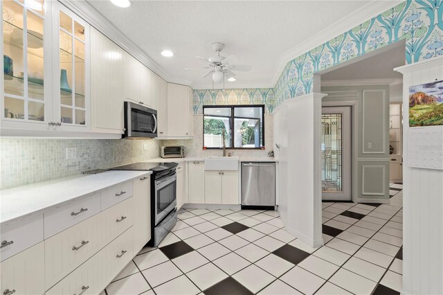 6818 Arbor Oaks Cir, Bradenton, FL 34209 - kitchen featuring stainless steel appliances, wallpapered walls, crown molding, ceiling fan, and white cabinets