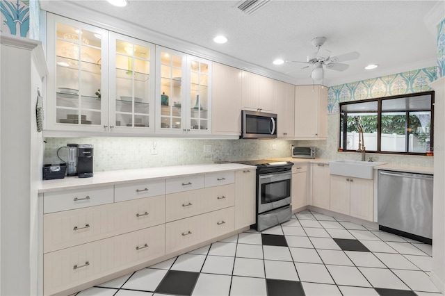 6818 Arbor Oaks Cir, Bradenton, FL 34209 - kitchen featuring appliances with stainless steel finishes, light countertops, ceiling fan, backsplash, and glass insert cabinets