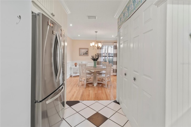 6818 Arbor Oaks Cir, Bradenton, FL 34209 - kitchen featuring freestanding refrigerator, a chandelier, crown molding, white cabinets, and light tile patterned floors