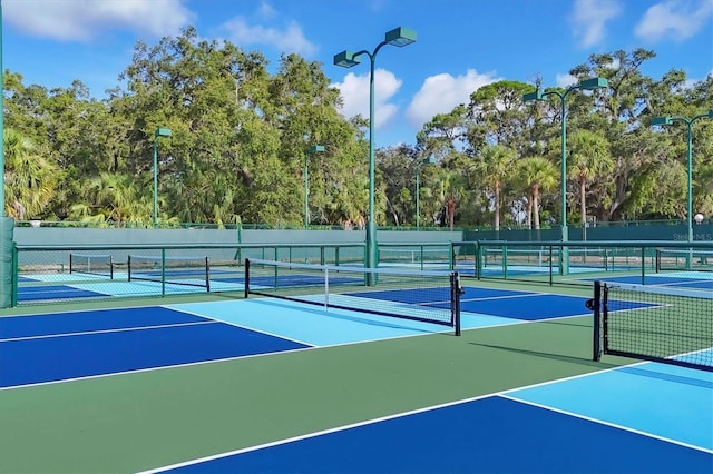 4658 Longwater Chase Unit 104, Sarasota, FL 34235 - view of tennis court featuring community basketball court and view of wooded area