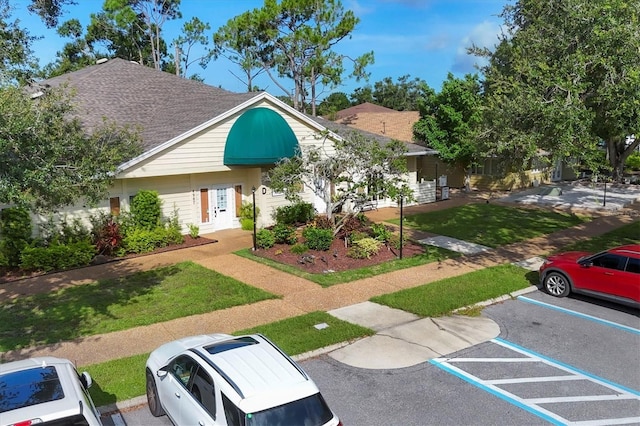 4658 Longwater Chase Unit 104, Sarasota, FL 34235 - view of front facade featuring uncovered parking, roof with shingles, a front yard, and french doors
