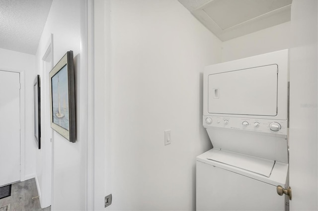 4658 Longwater Chase Unit 104, Sarasota, FL 34235 - washroom with stacked washer / dryer, wood finished floors, and a textured ceiling