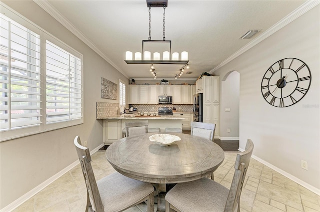 3911 91st Ave E, Parrish, FL 34219 - dining area featuring crown molding, arched walkways, stone tile flooring, and track lighting