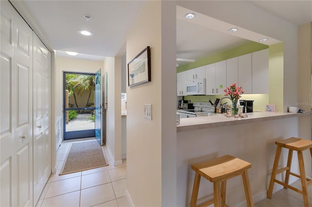 5705 Ashton Way Unit 5705, Sarasota, FL 34231 - kitchen featuring white appliances, a breakfast bar area, light tile patterned flooring, recessed lighting, and white cabinetry
