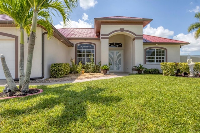 1402 SW 4th Ln, Cape Coral, FL 33991 - view of front of property with a standing seam roof, a metal roof, stucco siding, a front lawn, and an attached garage