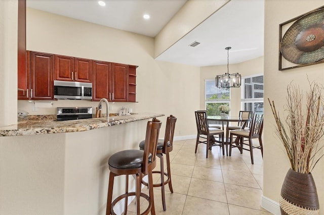 1402 SW 4th Ln, Cape Coral, FL 33991 - kitchen with stainless steel microwave, range, a chandelier, light stone countertops, and a breakfast bar