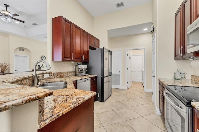 1402 SW 4th Ln, Cape Coral, FL 33991 - kitchen with stainless steel appliances, ceiling fan, light stone counters, light tile patterned floors, and a peninsula