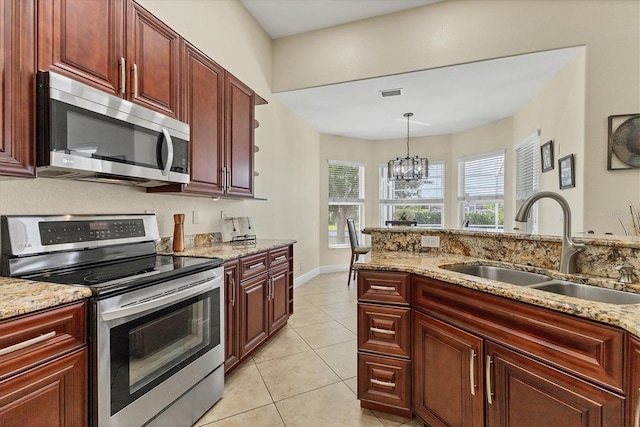 1402 SW 4th Ln, Cape Coral, FL 33991 - kitchen with appliances with stainless steel finishes, reddish brown cabinets, a chandelier, light tile patterned floors, and light stone countertops