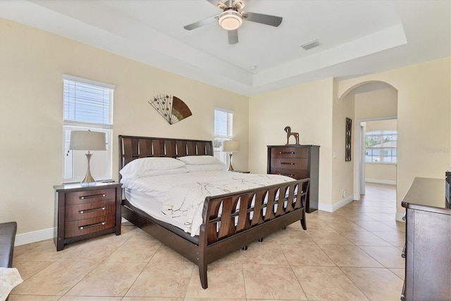 1402 SW 4th Ln, Cape Coral, FL 33991 - bedroom with arched walkways, light tile patterned flooring, a tray ceiling, and ceiling fan