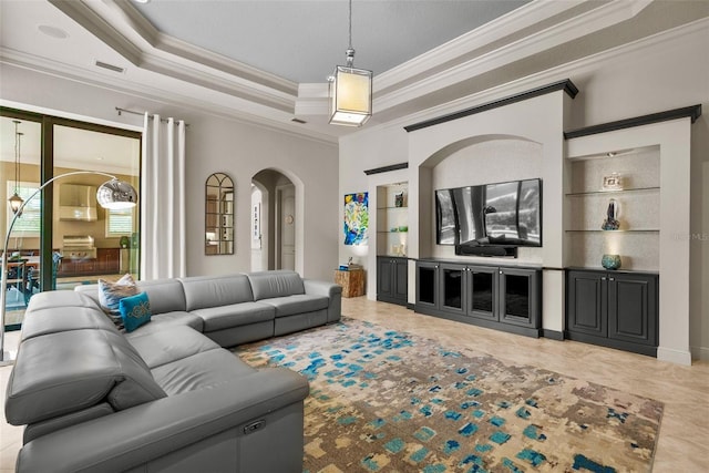 6926 Lacantera Cir, Lakewood Ranch, FL 34202 - living room with crown molding, built in shelves, a tray ceiling, and arched walkways