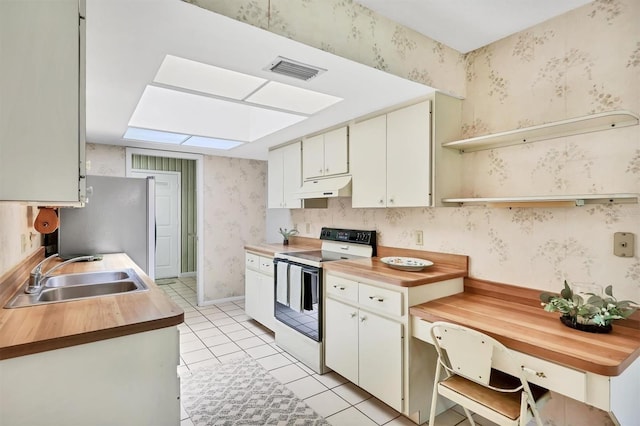 3557 Wilkinson Woods Dr, Sarasota, FL 34231 - kitchen featuring white electric range, wallpapered walls, under cabinet range hood, a skylight, and light tile patterned floors