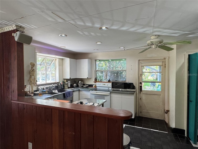 1109 Patterson Dr, Sarasota, FL 34234 - kitchen with electric stove, stainless steel microwave, white cabinetry, a peninsula, and recessed lighting
