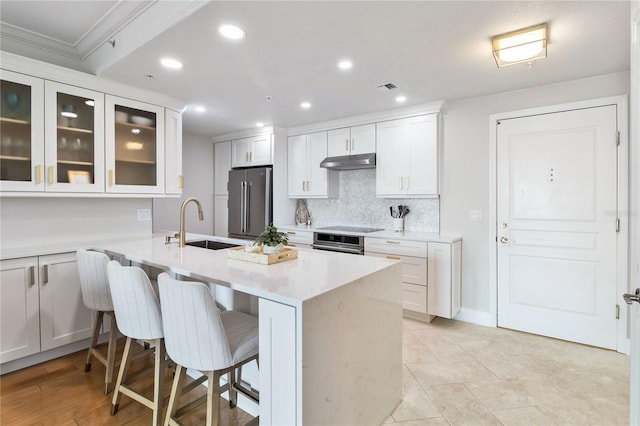750 N Tamiami Trl Unit 1616, Sarasota, FL 34236 - kitchen with under cabinet range hood, stainless steel appliances, a breakfast bar area, glass insert cabinets, and decorative backsplash