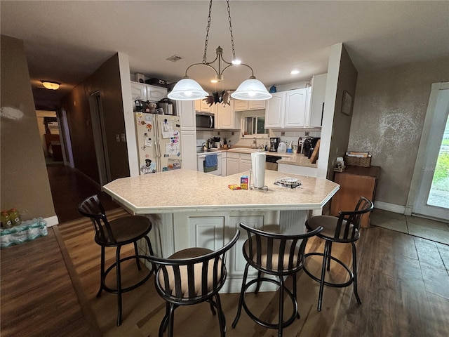 12345 Terra Ceia Ave, New Port Richey, FL 34654 - kitchen featuring white appliances, dark wood finished floors, light countertops, white cabinetry, and a kitchen breakfast bar