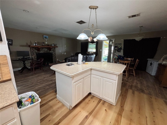 12345 Terra Ceia Ave, New Port Richey, FL 34654 - kitchen with light wood finished floors, light countertops, white cabinetry, and a stone fireplace