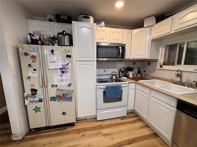 12345 Terra Ceia Ave, New Port Richey, FL 34654 - kitchen with stainless steel appliances, white cabinets, light wood finished floors, decorative backsplash, and light countertops