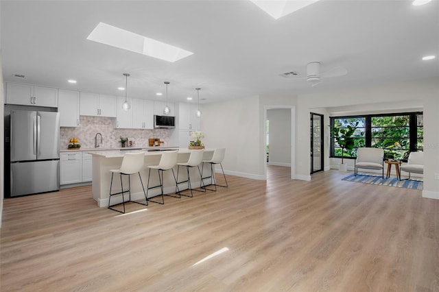 3518 Wilkinson Woods Dr Unit 11, Sarasota, FL 34231 - kitchen with stainless steel appliances, a skylight, recessed lighting, a kitchen island, and white cabinets