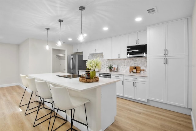 3518 Wilkinson Woods Dr Unit 11, Sarasota, FL 34231 - kitchen featuring appliances with stainless steel finishes, a breakfast bar, white cabinetry, a center island, and decorative backsplash
