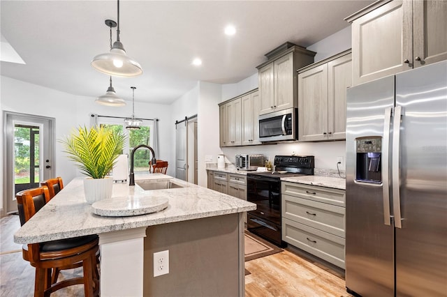 174 SW Caboose Dr, Fort White, FL 32038 - kitchen with stainless steel appliances, a barn door, a kitchen bar, light wood-style flooring, and a center island with sink