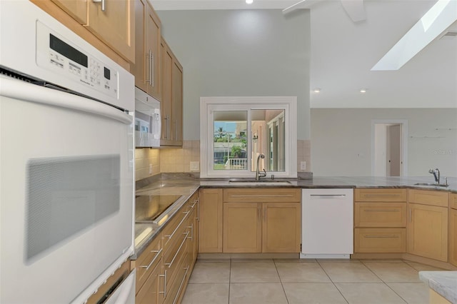 1236 Port Ln, Sarasota, FL 34242 - kitchen with white appliances, a skylight, decorative backsplash, light tile patterned floors, and dark stone countertops
