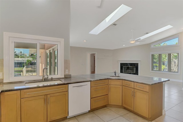 1236 Port Ln, Sarasota, FL 34242 - kitchen featuring white dishwasher, a skylight, vaulted ceiling, stone counters, and a premium fireplace