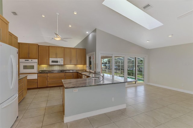 1236 Port Ln, Sarasota, FL 34242 - kitchen featuring white appliances, a warming drawer, light tile patterned floors, tasteful backsplash, and a skylight