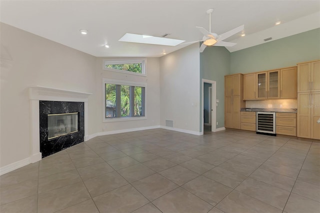 1236 Port Ln, Sarasota, FL 34242 - unfurnished living room featuring beverage cooler, high vaulted ceiling, light tile patterned floors, a high end fireplace, and a skylight