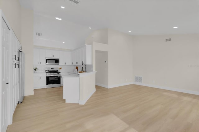 1820 Putney Cir, Orlando, FL 32837 - kitchen with appliances with stainless steel finishes, vaulted ceiling, open floor plan, light wood-style floors, and white cabinetry