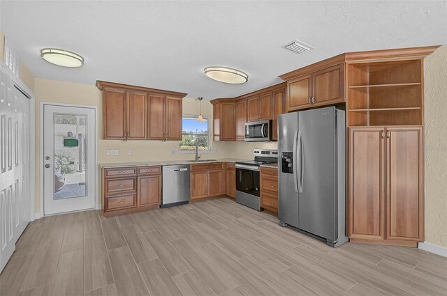 5830 Midnight Pass Rd Unit 108, Sarasota, FL 34242 - kitchen with stainless steel appliances, open shelves, brown cabinets, and light wood-style floors