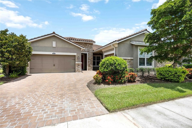 11680 Tapestry Ln, Venice, FL 34292 - view of front of property featuring stone siding, stucco siding, a garage, decorative driveway, and a tiled roof