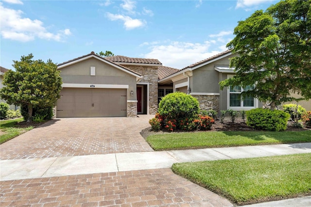 11680 Tapestry Ln, Venice, FL 34292 - view of front facade with stone siding, stucco siding, an attached garage, decorative driveway, and a tiled roof