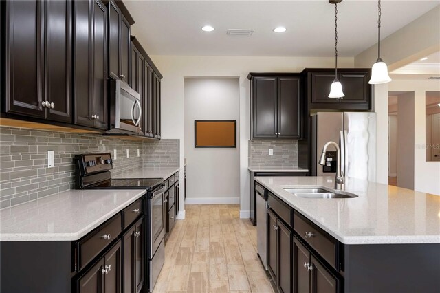 11680 Tapestry Ln, Venice, FL 34292 - kitchen featuring stainless steel appliances, a kitchen island with sink, tasteful backsplash, decorative light fixtures, and light stone countertops
