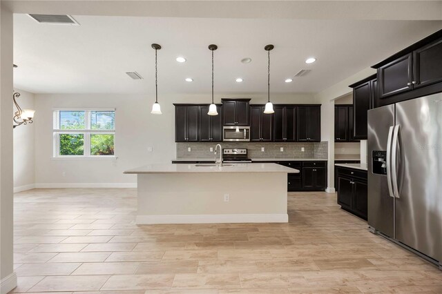 11680 Tapestry Ln, Venice, FL 34292 - kitchen with stainless steel appliances, light countertops, decorative backsplash, recessed lighting, and a center island with sink
