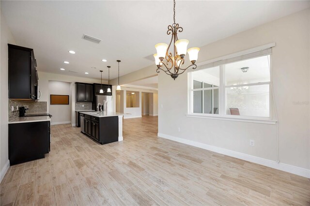 11680 Tapestry Ln, Venice, FL 34292 - kitchen with light countertops, open floor plan, tasteful backsplash, a chandelier, and light wood finished floors