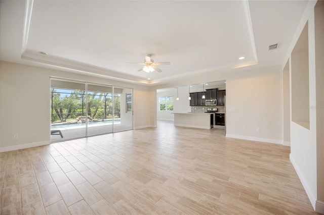 11680 Tapestry Ln, Venice, FL 34292 - unfurnished living room featuring a tray ceiling, ceiling fan, light wood-type flooring, and recessed lighting