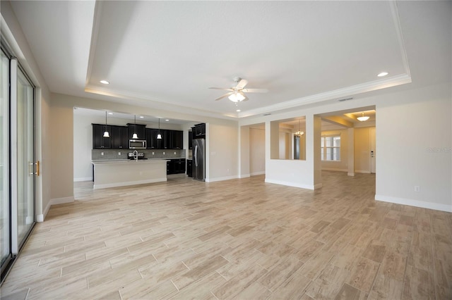 11680 Tapestry Ln, Venice, FL 34292 - unfurnished living room featuring a raised ceiling, ceiling fan, light wood finished floors, recessed lighting, and ornamental molding