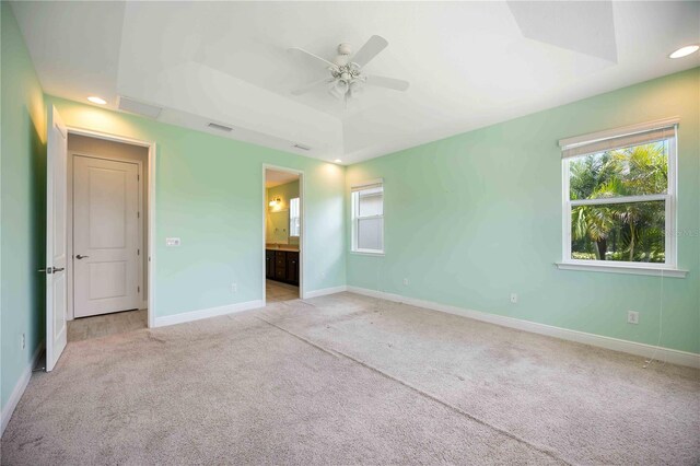 11680 Tapestry Ln, Venice, FL 34292 - unfurnished bedroom featuring light colored carpet, a raised ceiling, recessed lighting, ensuite bathroom, and a ceiling fan