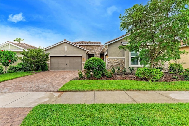 11680 Tapestry Ln, Venice, FL 34292 - view of front of property featuring stucco siding, stone siding, driveway, an attached garage, and a front yard