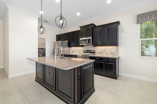 13789 Old Creek Ct, Parrish, FL 34219 - kitchen with washer and clothes dryer, appliances with stainless steel finishes, tasteful backsplash, a kitchen island with sink, and dark cabinets