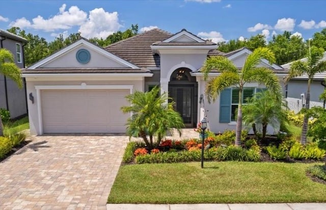 3605 Wild Blossom Pl, Parrish, FL 34219 - mediterranean / spanish house featuring stucco siding, decorative driveway, a garage, a front yard, and a tiled roof