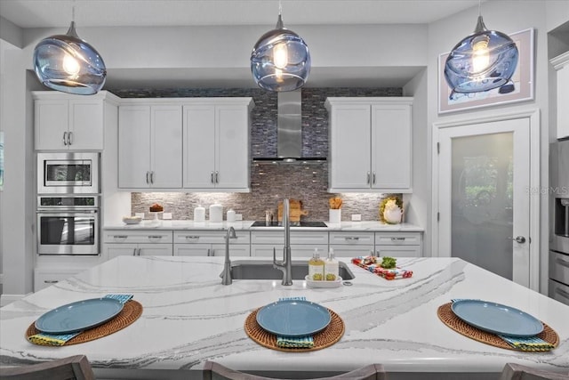 3605 Wild Blossom Pl, Parrish, FL 34219 - kitchen featuring appliances with stainless steel finishes, wall chimney range hood, hanging light fixtures, decorative backsplash, and light stone counters