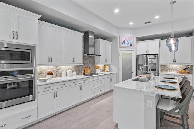 3605 Wild Blossom Pl, Parrish, FL 34219 - kitchen featuring appliances with stainless steel finishes, wall chimney range hood, decorative backsplash, white cabinets, and recessed lighting