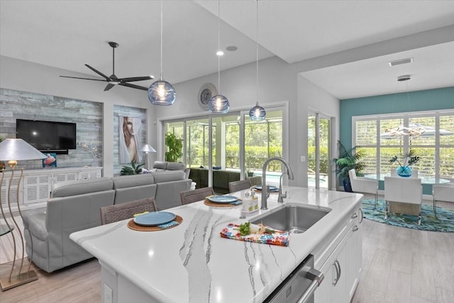 3605 Wild Blossom Pl, Parrish, FL 34219 - kitchen featuring white cabinets, open floor plan, light stone counters, decorative light fixtures, and light wood-type flooring