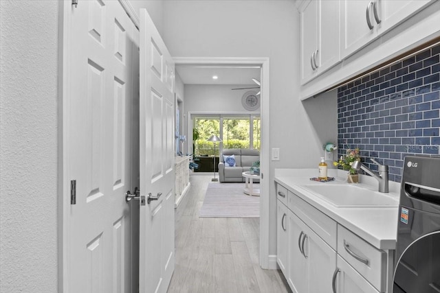 3605 Wild Blossom Pl, Parrish, FL 34219 - kitchen with light countertops, white cabinets, washer / clothes dryer, light wood-style flooring, and recessed lighting