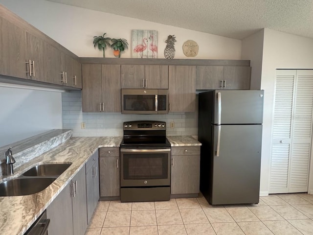 7301 29th Avenue Dr W Unit 310, Bradenton, FL 34209 - kitchen featuring appliances with stainless steel finishes, light tile patterned floors, tasteful backsplash, light stone counters, and a textured ceiling