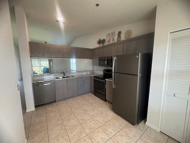 7301 29th Avenue Dr W Unit 310, Bradenton, FL 34209 - kitchen with appliances with stainless steel finishes, light countertops, light tile patterned floors, vaulted ceiling, and a textured ceiling