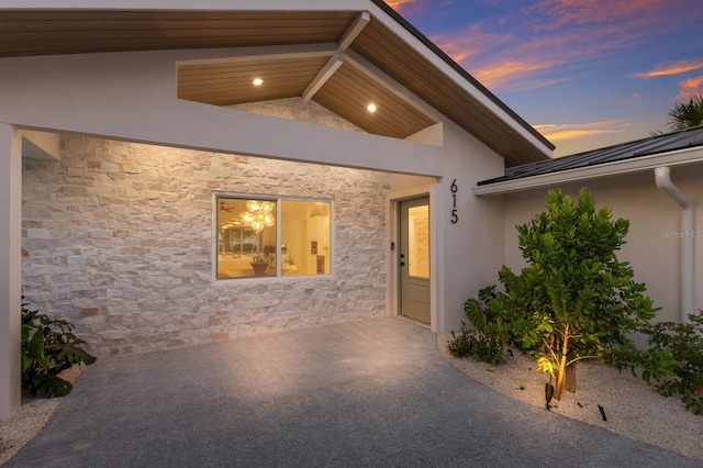 615 Concord Ln, Holmes Beach, FL 34217 - exterior entry at dusk featuring stone siding, stucco siding, and a patio area