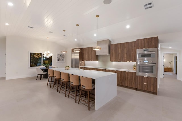 615 Concord Ln, Holmes Beach, FL 34217 - kitchen featuring modern cabinets, wall chimney exhaust hood, stainless steel appliances, a spacious island, and brown cabinetry