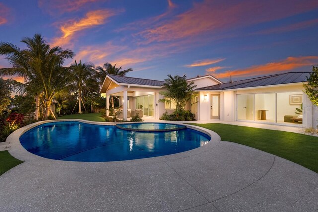 615 Concord Ln, Holmes Beach, FL 34217 - pool at dusk with a patio area, a lawn, and a pool with connected hot tub